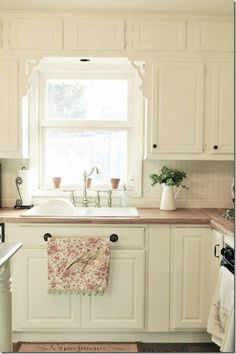 a kitchen with white cabinets and wooden floors