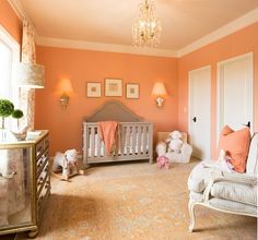 a baby's room with an orange wall and chandelier hanging from the ceiling