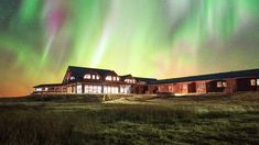 the aurora bore is shining brightly in the sky above a large house on a hill