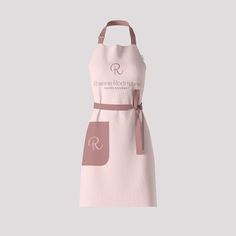 a pink apron with the letter r on it and a brown ribbon around the neck