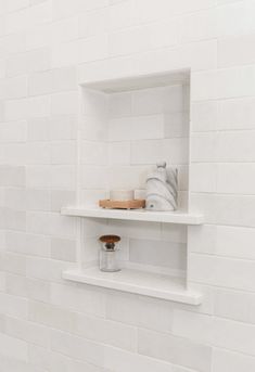 a white bathroom with two shelves on the wall