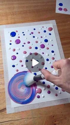 a person is using a paintbrush to create an art project with circles and dots