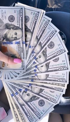 a woman's hand holding money in her car