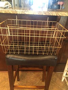 a metal basket sitting on top of a wooden stool in front of a kitchen counter