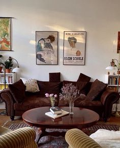 a living room with couches, chairs and pictures on the wall above them is filled with books