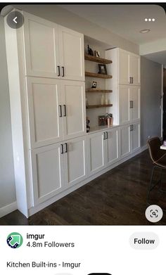 an image of a kitchen with white cabinets and wood flooring on the side wall