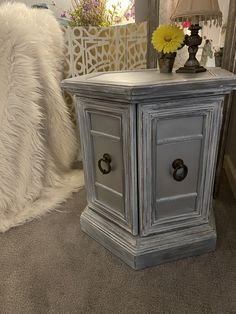 a white and gray side table sitting on top of a carpeted floor next to a mirror