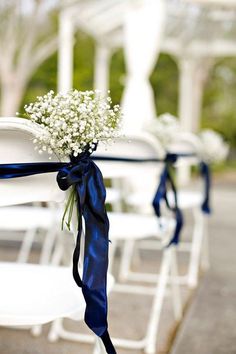 white chairs with blue ribbons and baby's breath flowers tied to the back of them