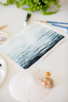 an art work is being displayed on a table with paint and watercolor pencils