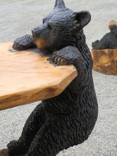 a black bear statue sitting on top of a wooden bench