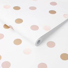 a white and pink polka dot wallpaper with gold dots on the top, as well as a roll of tape