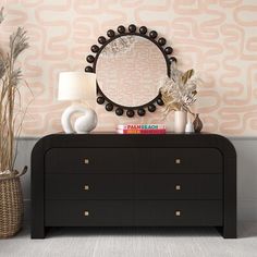 a dresser with a mirror, vases and plants on it in front of a wallpapered background