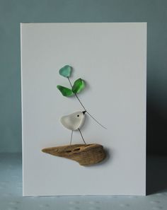 a greeting card with a bird on a rock and green leaves in the shape of a plant