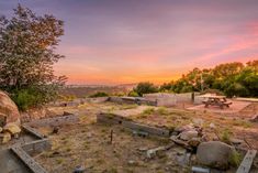 an empty field with rocks and trees in the background at sunset or sunrise, as seen from above