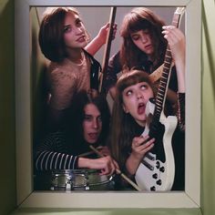 a group of young women standing next to each other in front of a mirror holding guitars