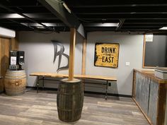 an empty room with wooden barrels and a sign on the wall that says drink the east