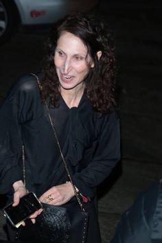 a woman in black carrying a purse and smiling