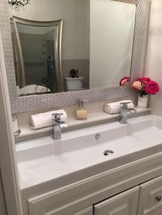 a white bathroom sink sitting under a large mirror