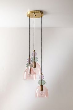 three pink glass pendant lights hanging from a ceiling