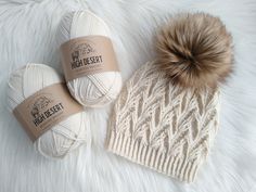 two balls of white yarn and a brown pom - pom