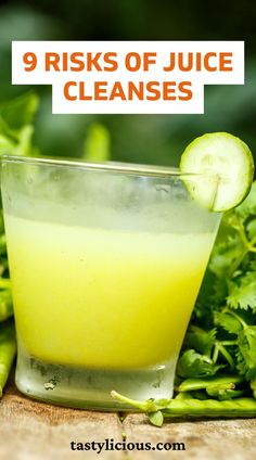 a glass filled with juice and cucumbers on top of a wooden table