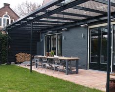 an outdoor dining area with table and chairs under a pergolated awning over the patio