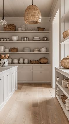 a kitchen filled with lots of white dishes and baskets on top of wooden shelves next to cabinets