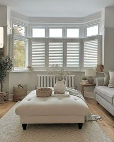 a living room filled with furniture and windows covered in shades of white shuttered blinds