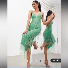 a woman in a green dress standing next to a mirror with her reflection on it