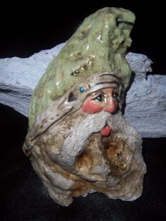 a ceramic figurine is sitting on a piece of driftwood