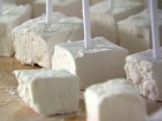 several marshmallows on a wooden table with candles sticking out of them,