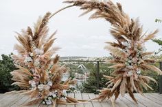 two wreaths made out of dried grass and flowers on a wooden deck overlooking the water