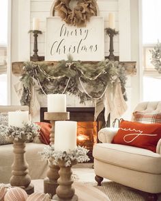 a living room decorated for christmas with candles and wreaths on the fireplace mantel