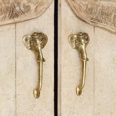 an elephant head door handle is shown on the side of a white marble cabinet with gold accents