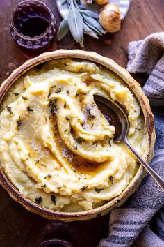 mashed potatoes in a bowl with a spoon and garlic on the table next to it