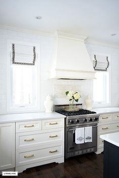 a stove top oven sitting inside of a kitchen next to white cabinets and counter tops