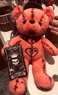 a pink teddy bear with black ink on it's face and chest, sitting on a counter