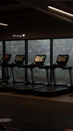 there are many treadmills in the gym with windows looking out on the trees