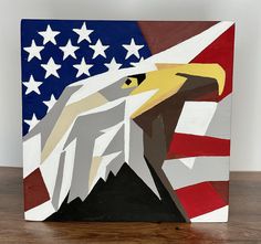 an eagle with the american flag painted on it's back is sitting on a wooden surface