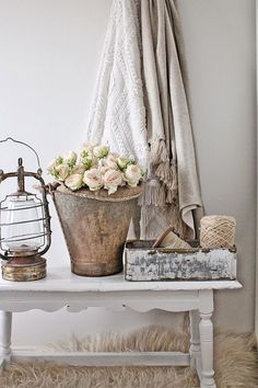 a white table topped with a potted plant next to a basket filled with flowers