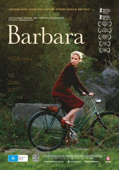 a woman riding a bike on top of a lush green field