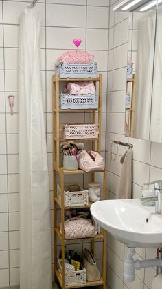 a bathroom with a sink and shelving unit next to a shower curtain in the corner