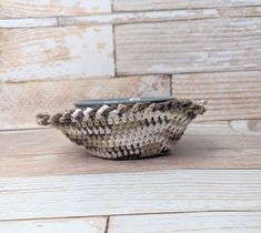 a woven bowl sitting on top of a wooden table