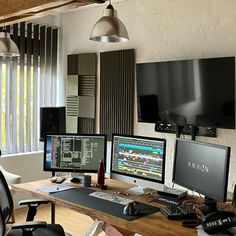 two computer monitors sitting on top of a wooden desk