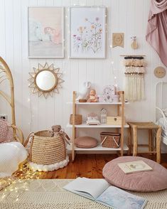 a room with white walls and wooden flooring, pink furniture and pictures on the wall