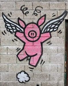 a pig painted on the side of a brick wall next to a door with wings