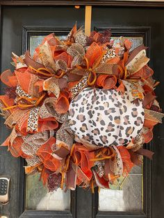 a leopard print and orange mesh wreath on a front door with an animal print bow