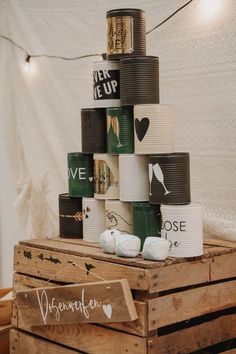 a stack of coffee cups sitting on top of a wooden crate next to string lights