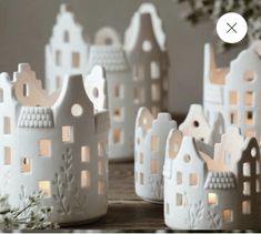 several small white houses are sitting on a table with candles in the shape of houses