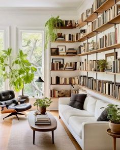 a living room filled with lots of furniture and bookshelves next to a window